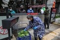 中国中部・湖北省武漢で、ゲート越しに野菜を受け取る住民たち（2020年3月3日撮影）。(c)AFP