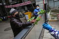 中国中部・湖北省武漢で、ゲート越しに野菜の代金を支払う住民（2020年3月3日撮影）。(c)AFP