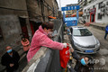 中国中部・湖北省武漢で、壁越しに食料を受け取る住民（2020年3月3日撮影）。(c)AFP