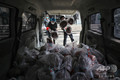 中国中部・湖北省武漢で、住民に届ける野菜を配送車に積み込むスーパーマーケットの従業員たち（2020年3月5日撮影）。(c)AFP
